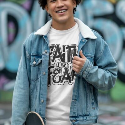 <p>Youth white "faith over fear tee" featuring bold black lettering, worn under a denim jacket, perfect for casual style.</p>
